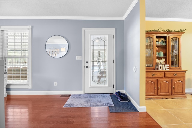 entryway featuring wood finished floors, baseboards, and ornamental molding