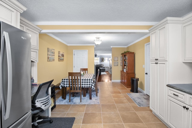 dining space featuring crown molding, light tile patterned floors, baseboards, and a textured ceiling