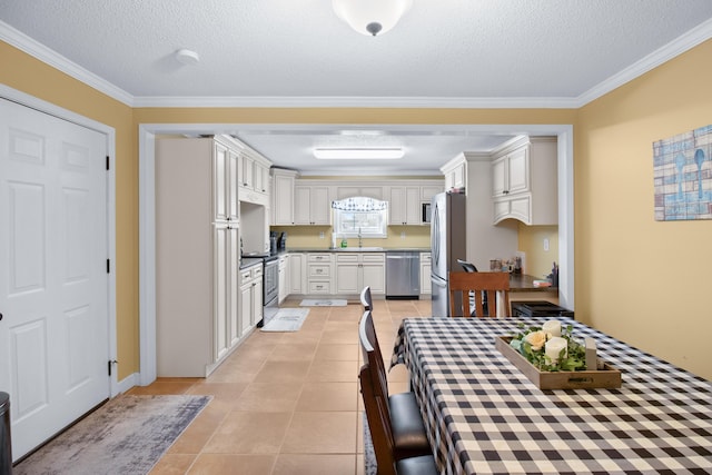 kitchen with light tile patterned flooring, a textured ceiling, stainless steel appliances, and crown molding