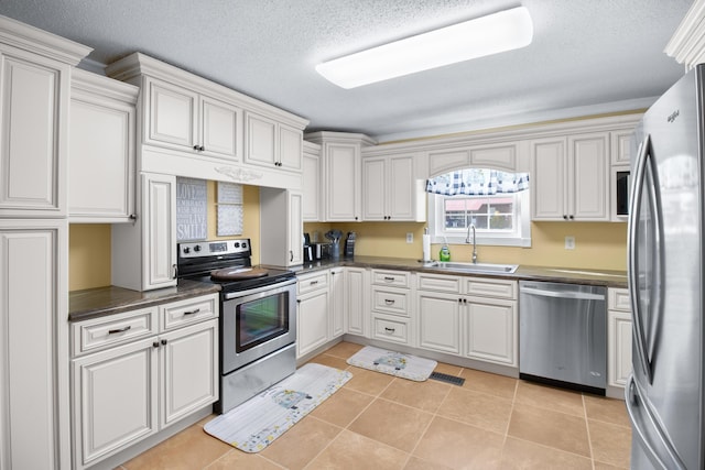 kitchen featuring a sink, stainless steel appliances, dark countertops, and light tile patterned floors