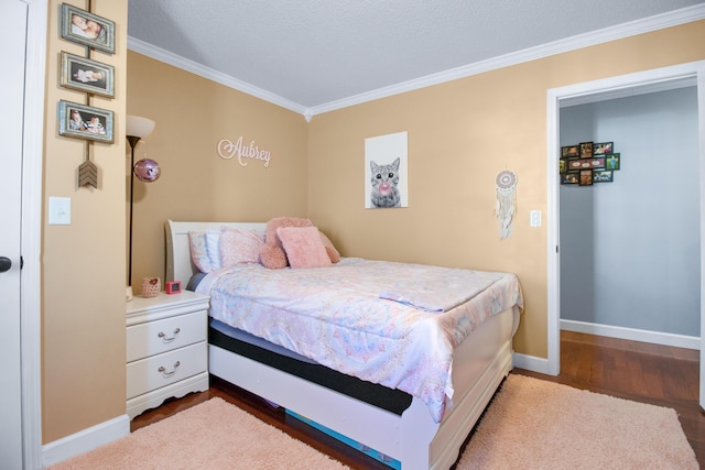 bedroom featuring baseboards, wood finished floors, and crown molding