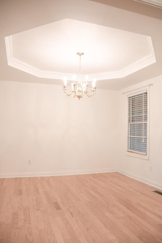 781 E Lexington St, Harrodsburg, KY 40330 - unfurnished room featuring a raised ceiling, a chandelier, crown molding, light wood-type flooring, and baseboards