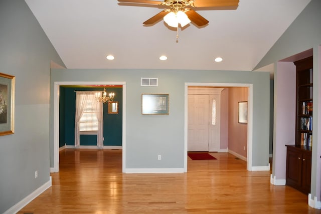 interior space featuring ceiling fan with notable chandelier, light hardwood / wood-style flooring, and lofted ceiling