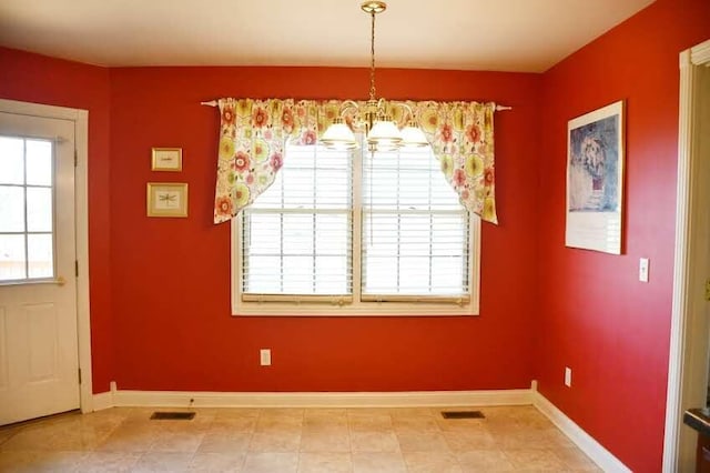 unfurnished dining area with tile patterned flooring, a healthy amount of sunlight, and a notable chandelier