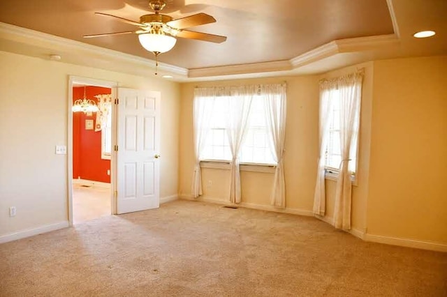 carpeted spare room with ceiling fan, a raised ceiling, plenty of natural light, and ornamental molding