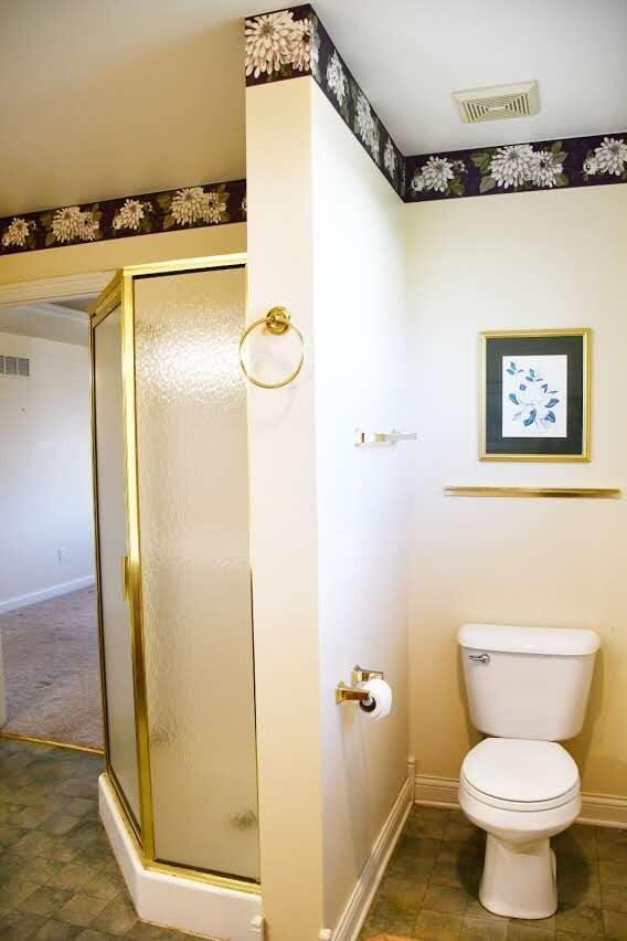 bathroom with toilet and a shower with door