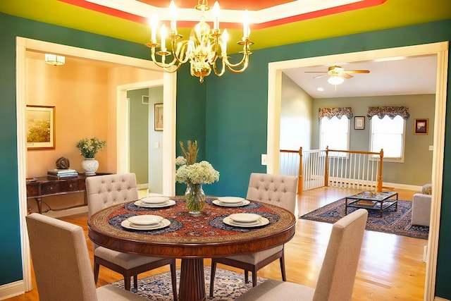 dining room with ceiling fan with notable chandelier and hardwood / wood-style flooring