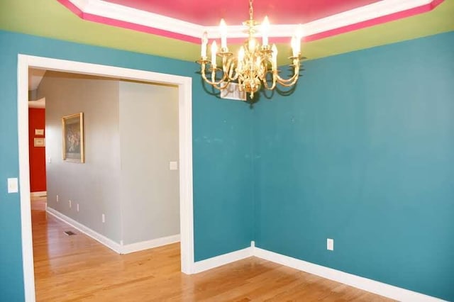 empty room with hardwood / wood-style flooring and a notable chandelier