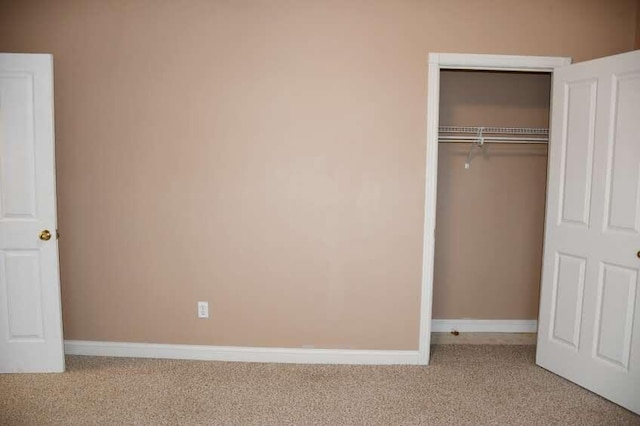 unfurnished bedroom featuring light carpet and a closet