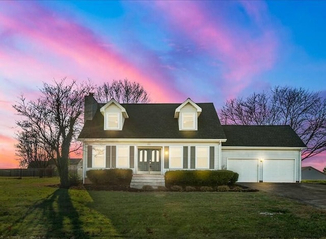 cape cod home featuring a lawn, a garage, and french doors