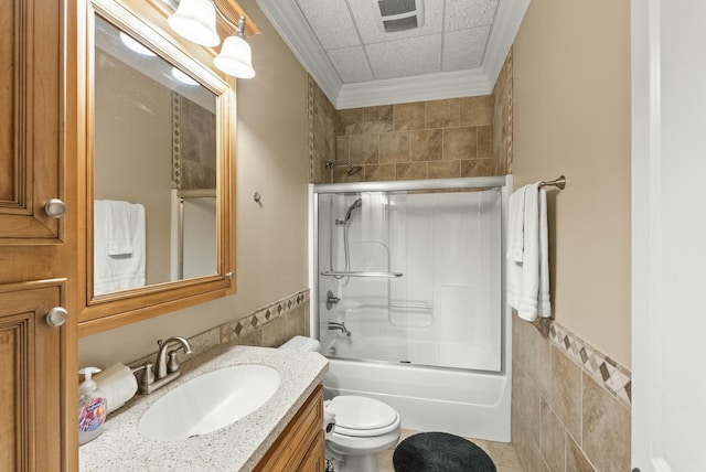 full bathroom with toilet, crown molding, bath / shower combo with glass door, tile walls, and vanity