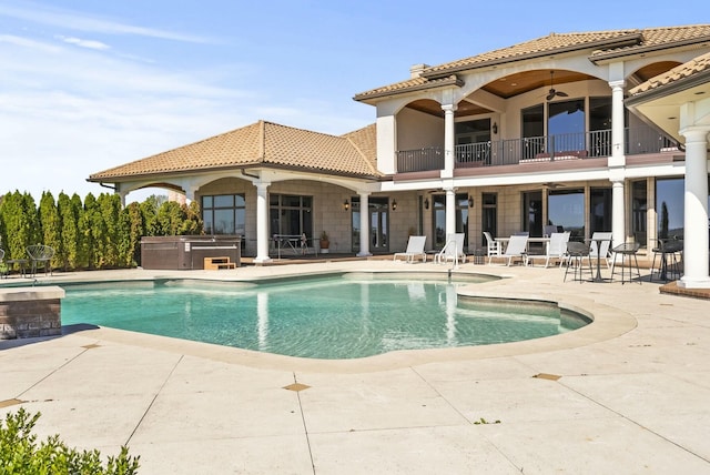 back of property with a balcony, ceiling fan, and a patio area