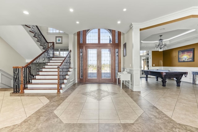 tiled entrance foyer with french doors, billiards, crown molding, a chandelier, and a raised ceiling