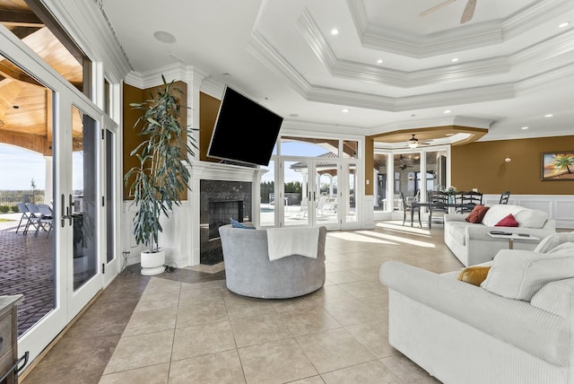 living room featuring a premium fireplace, light tile patterned floors, a tray ceiling, crown molding, and french doors