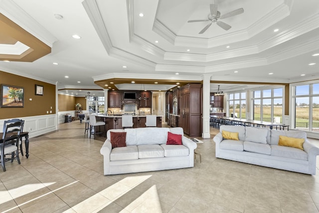 living room with ornamental molding, a tray ceiling, and light tile patterned floors