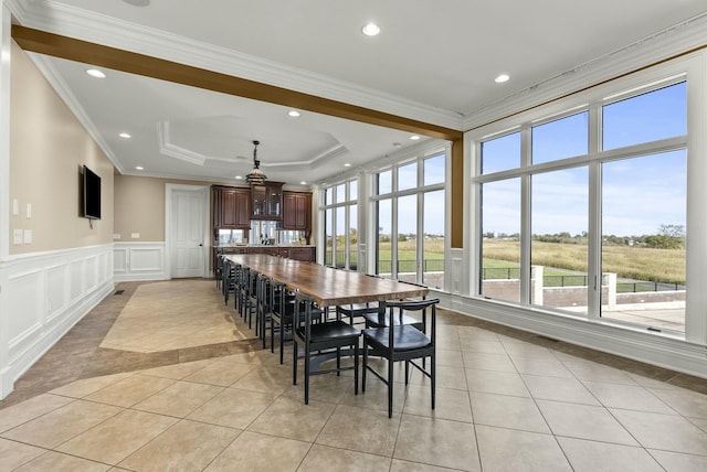 tiled dining area with crown molding and a tray ceiling