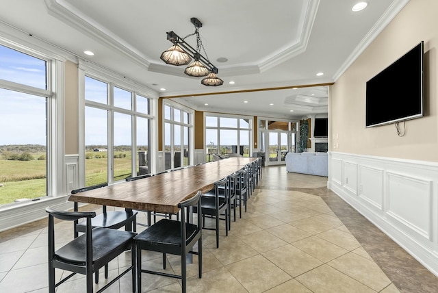 dining area featuring light tile patterned floors, a tray ceiling, a wealth of natural light, and ornamental molding