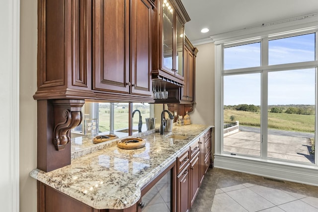 kitchen with light stone counters, ornamental molding, light tile patterned flooring, and sink