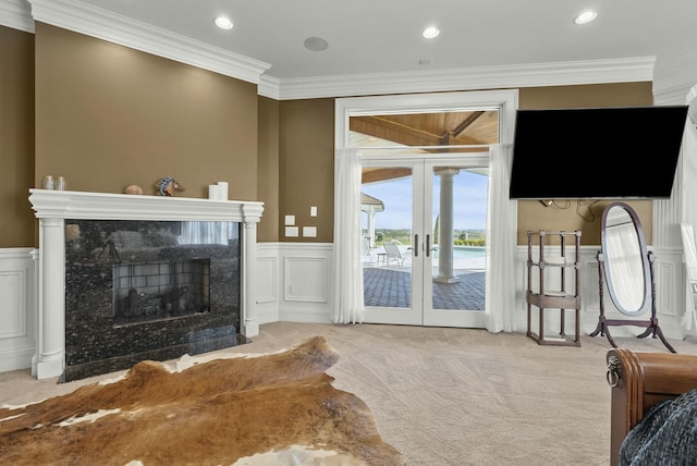 living room featuring french doors, light colored carpet, a premium fireplace, and crown molding