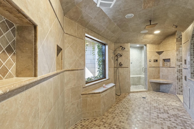 bathroom featuring a shower with door, vaulted ceiling, tile patterned flooring, and tile walls