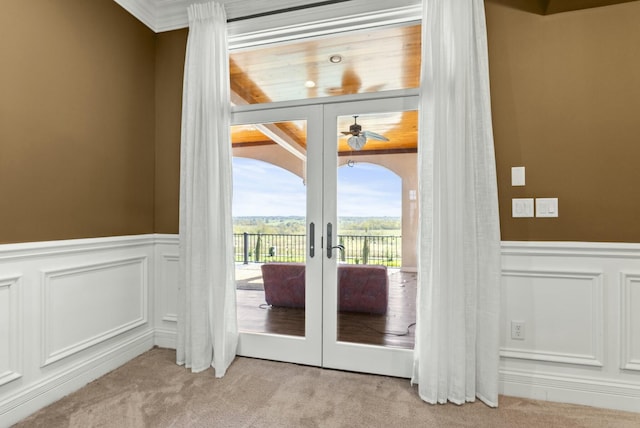 entryway with ornamental molding, light colored carpet, ceiling fan, and french doors