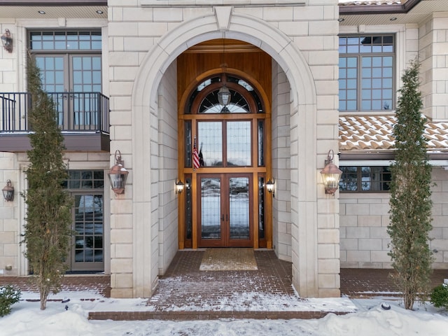 snow covered property entrance featuring french doors