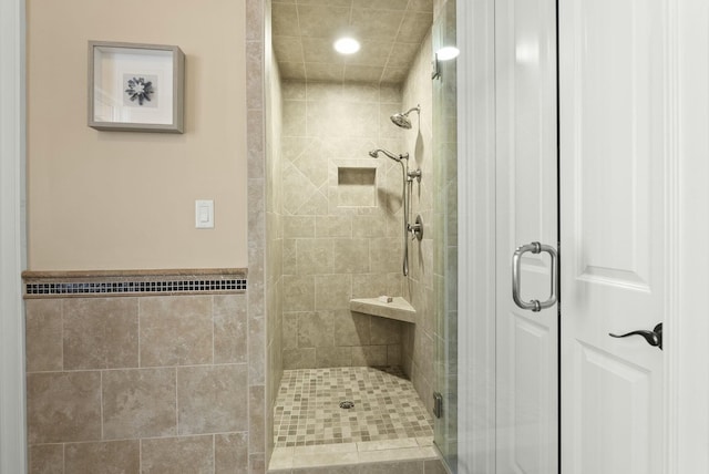 bathroom featuring a shower with door and tile walls