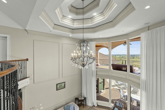 room details featuring a raised ceiling, ornamental molding, and a notable chandelier