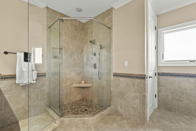 bathroom with crown molding, a shower with door, and tile walls