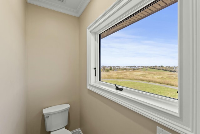 bathroom featuring crown molding, toilet, and a rural view