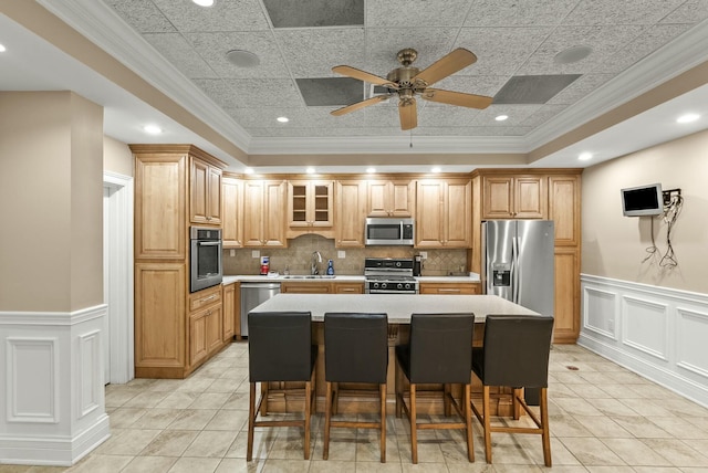 kitchen featuring crown molding, a breakfast bar area, a center island, and appliances with stainless steel finishes