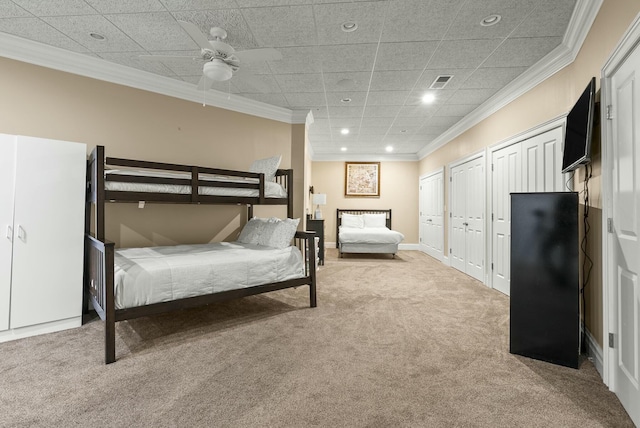 bedroom with multiple closets, crown molding, light colored carpet, and ceiling fan