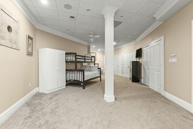 carpeted bedroom featuring crown molding, multiple closets, and a drop ceiling