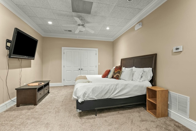 carpeted bedroom with ornamental molding, ceiling fan, and a closet