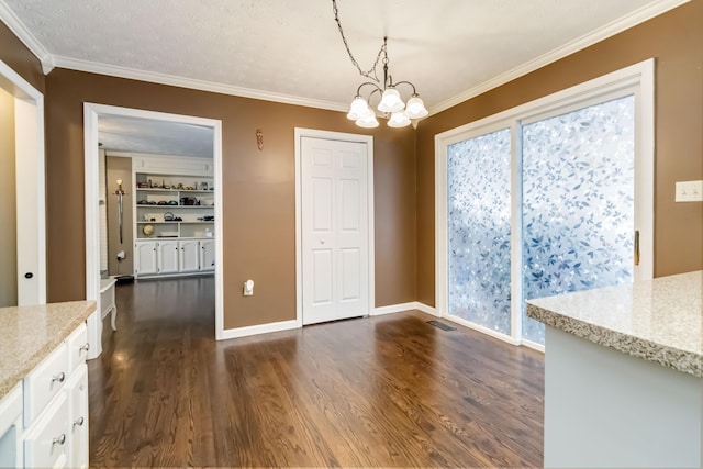 unfurnished dining area with an inviting chandelier, ornamental molding, dark hardwood / wood-style floors, and a textured ceiling