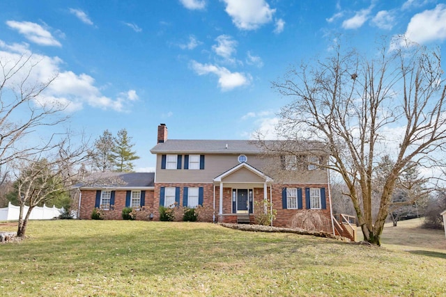 view of front of property with brick siding, a chimney, a front lawn, and fence