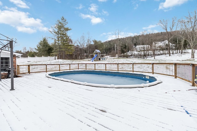 snow covered pool featuring a playground and a wooden deck