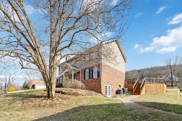 view of side of home with a wooden deck, a yard, and central AC