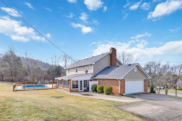 back of property with a fenced in pool, a lawn, and a sunroom