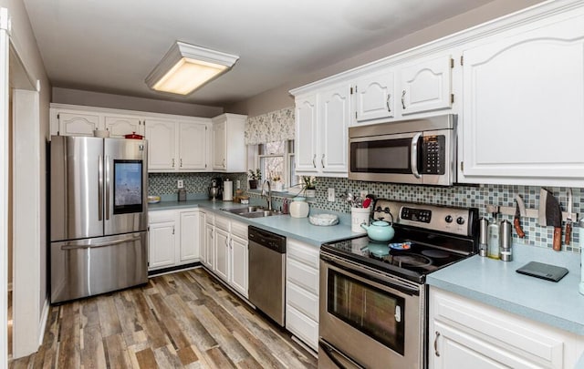 kitchen featuring sink, dark wood-type flooring, stainless steel appliances, decorative backsplash, and white cabinets