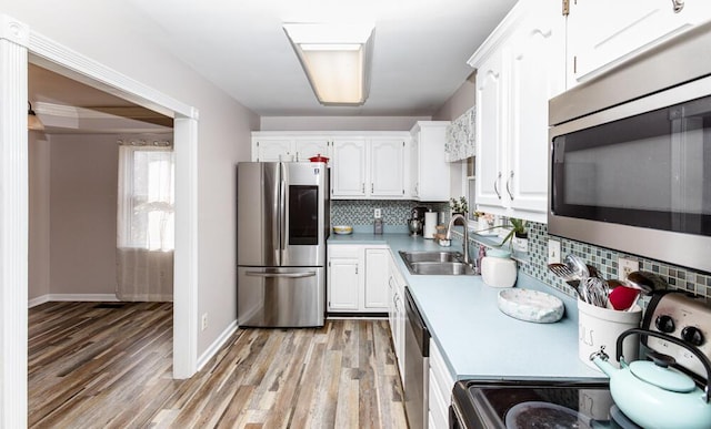 kitchen featuring decorative backsplash, appliances with stainless steel finishes, white cabinetry, and sink