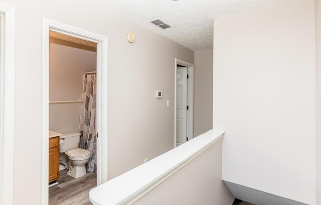 corridor with a textured ceiling and light hardwood / wood-style floors