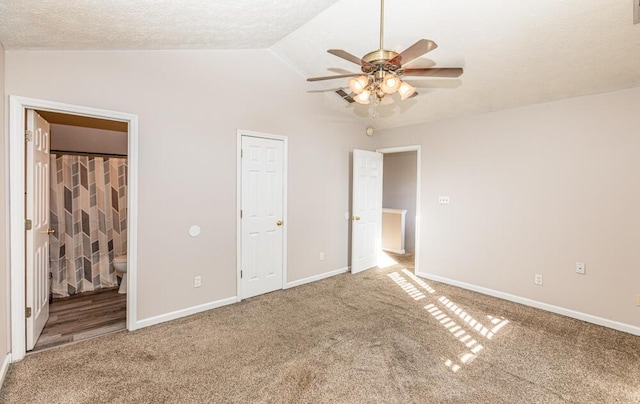 unfurnished bedroom featuring vaulted ceiling, ceiling fan, a textured ceiling, connected bathroom, and carpet floors