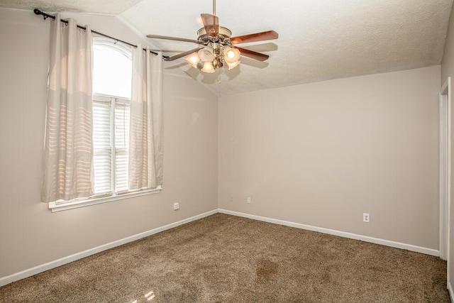 carpeted empty room featuring a textured ceiling, vaulted ceiling, and ceiling fan