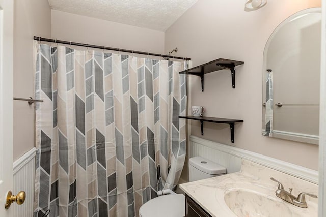 bathroom featuring a shower with curtain, vanity, a textured ceiling, and toilet