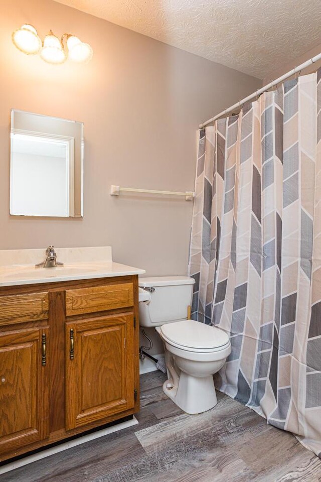 bathroom featuring hardwood / wood-style floors, vanity, a textured ceiling, and toilet