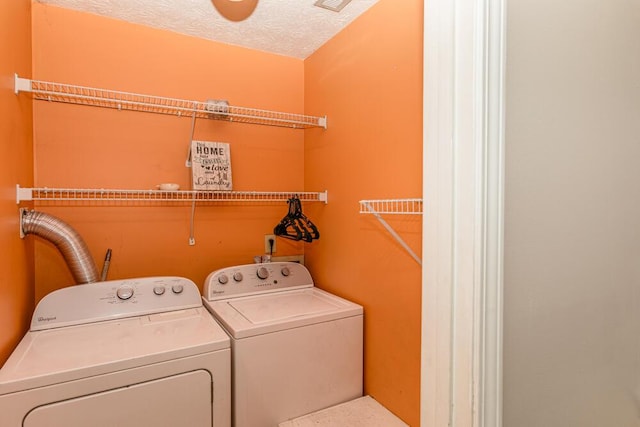 washroom featuring a textured ceiling and washer and clothes dryer