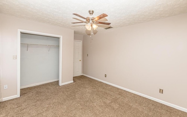 unfurnished bedroom featuring carpet flooring, a textured ceiling, a closet, and ceiling fan