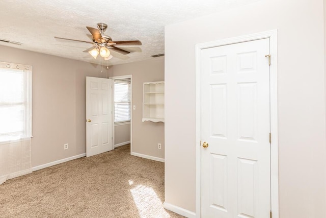 unfurnished bedroom featuring a textured ceiling, light colored carpet, and ceiling fan