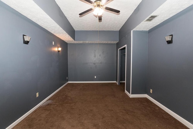 spare room featuring ceiling fan, a textured ceiling, and dark colored carpet